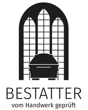 Ein schwarzer Sarg steht vor einem gotischen Fenster mit Gitter im Hintergrund