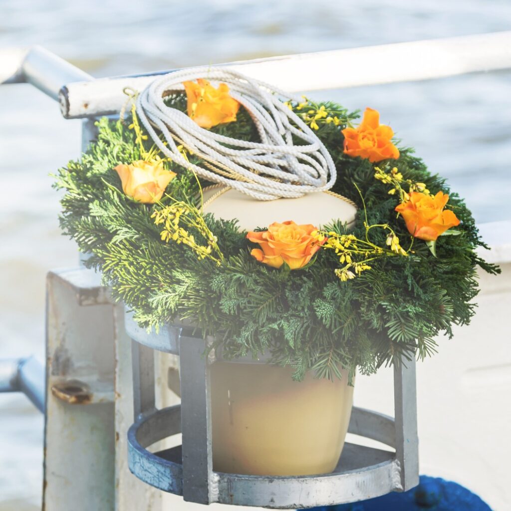 Urne mit Blumen auf einem Schiff an einer Seebestattung