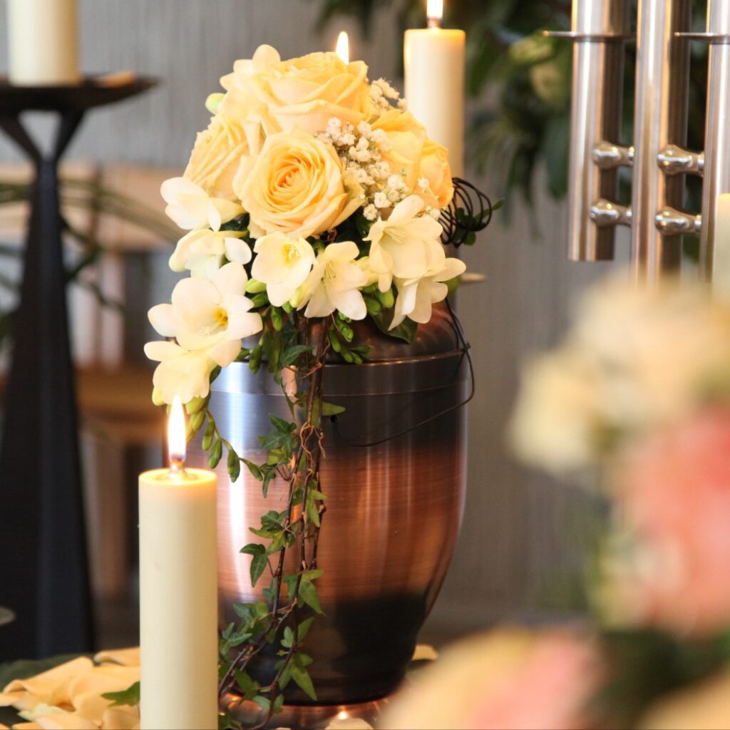 Blumenschmuck mit weißen Rosen auf einer Urne