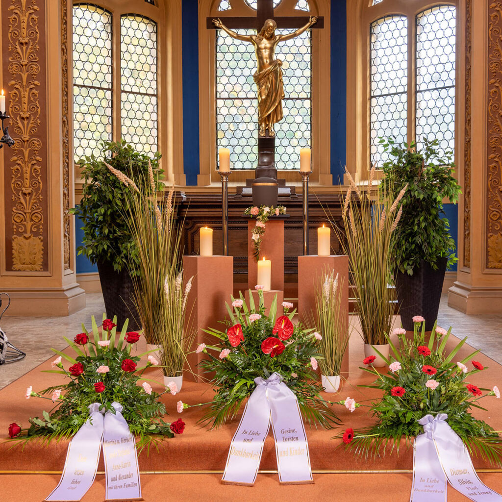 Eine festlich geschmückte Kirche mit Blumen, Kerzen und einer goldenen Jesusstatue