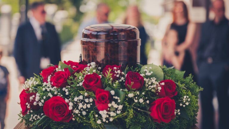 Urne mit der Asche des Verstorbenen und Blumen bei einer Beerdigung.